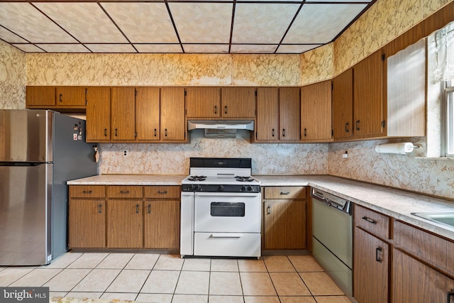 kitchen with light tile patterned floors, stainless steel fridge, dishwasher, backsplash, and white gas stove