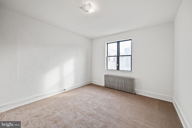 unfurnished room featuring radiator heating unit and carpet floors