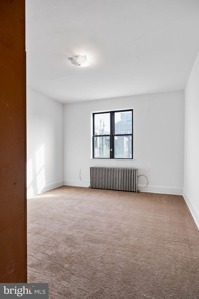 unfurnished room featuring radiator heating unit and carpet floors