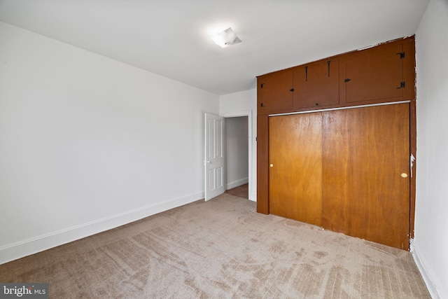 unfurnished bedroom with light colored carpet and a closet