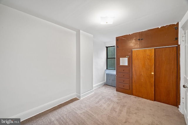 unfurnished bedroom with radiator heating unit and light carpet