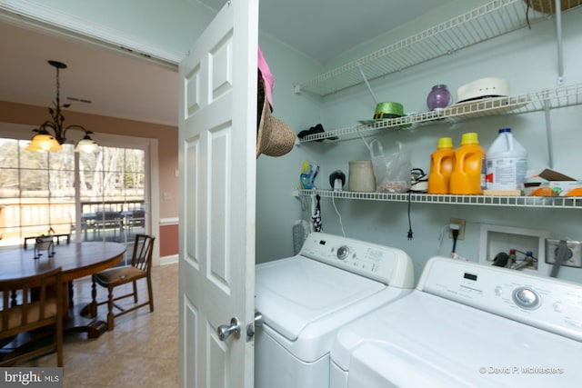 laundry area with tile patterned flooring, washer and dryer, and an inviting chandelier