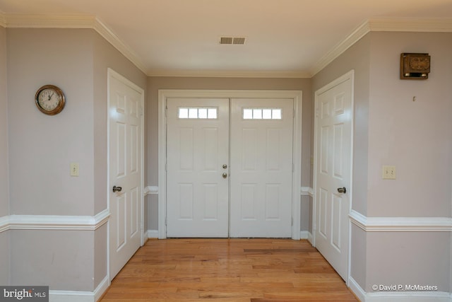 entrance foyer with crown molding and light hardwood / wood-style flooring