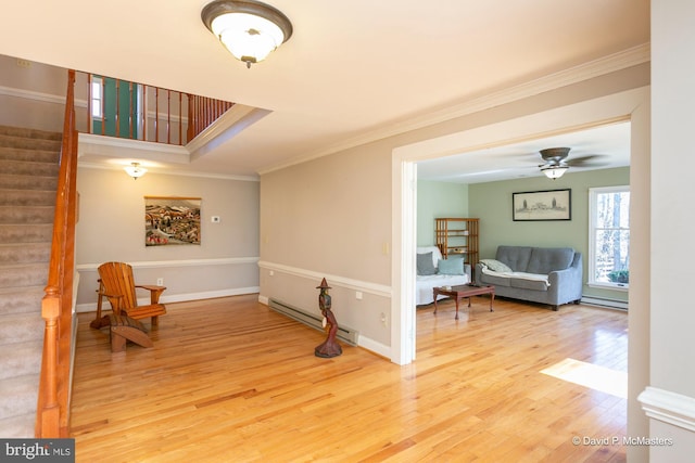 interior space with hardwood / wood-style flooring, ornamental molding, a baseboard heating unit, and a tray ceiling