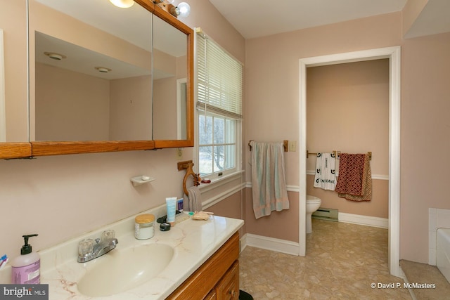 bathroom featuring vanity, a bathtub, baseboard heating, and toilet