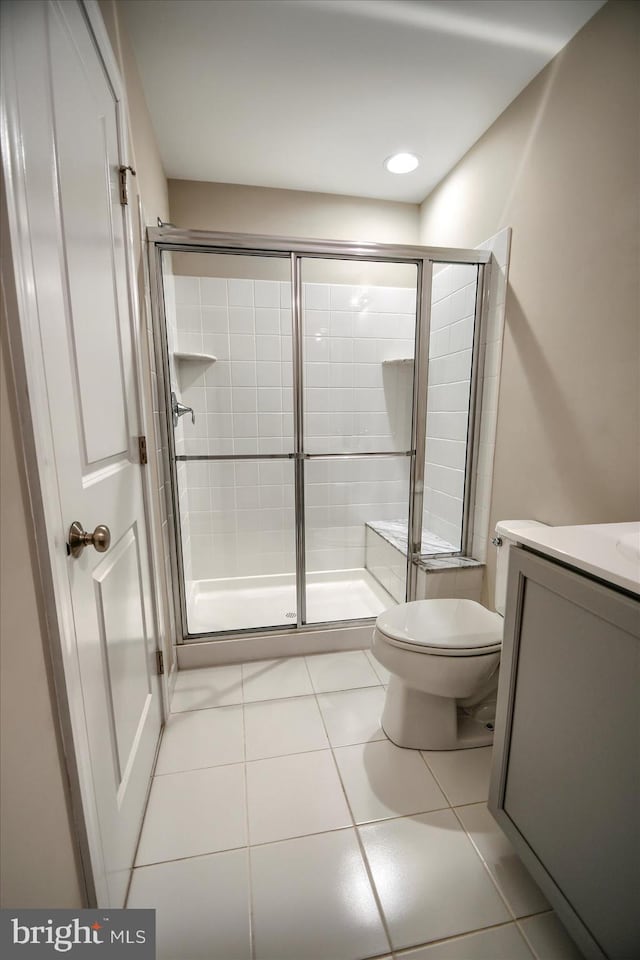 bathroom with vanity, tile patterned floors, a shower with door, and toilet