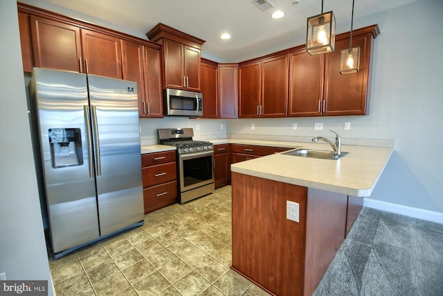 kitchen with appliances with stainless steel finishes, decorative light fixtures, kitchen peninsula, and sink