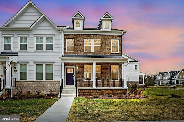 view of front of home featuring covered porch and a lawn