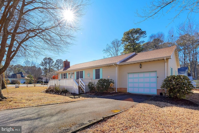 ranch-style house featuring a porch, an attached garage, driveway, a front lawn, and a chimney