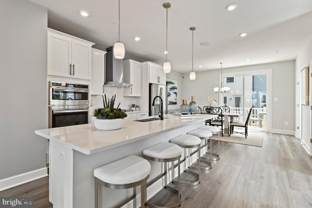 kitchen featuring white cabinetry, a large island, decorative light fixtures, and stainless steel appliances