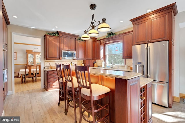 kitchen with light stone counters, appliances with stainless steel finishes, decorative light fixtures, and tasteful backsplash