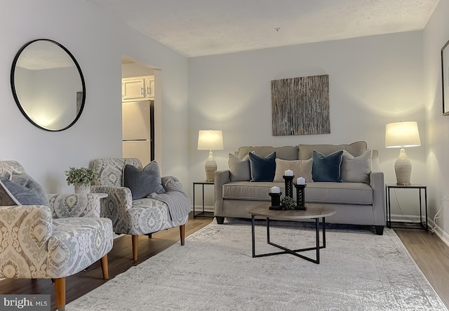 living area with a textured ceiling, baseboards, and wood finished floors