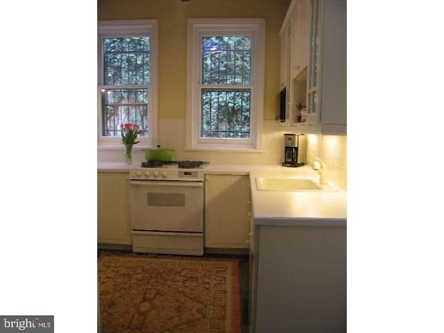 kitchen featuring sink, tasteful backsplash, and white gas range oven