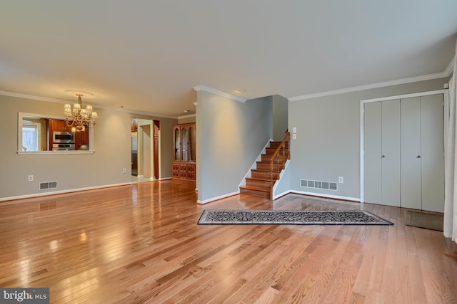 unfurnished living room with crown molding, an inviting chandelier, and light hardwood / wood-style floors