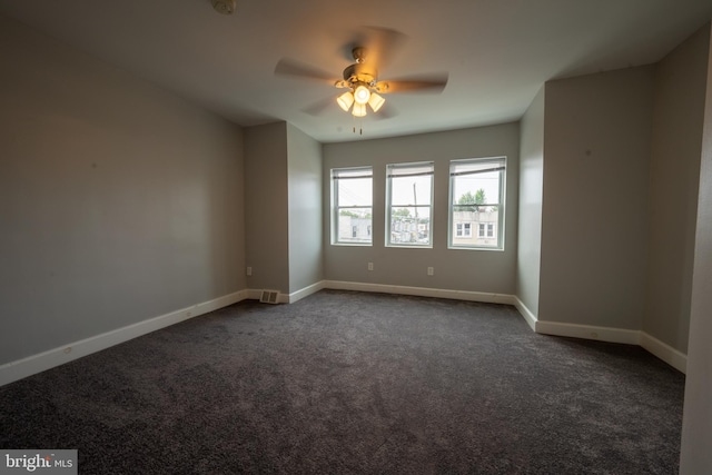 spare room featuring ceiling fan and dark carpet