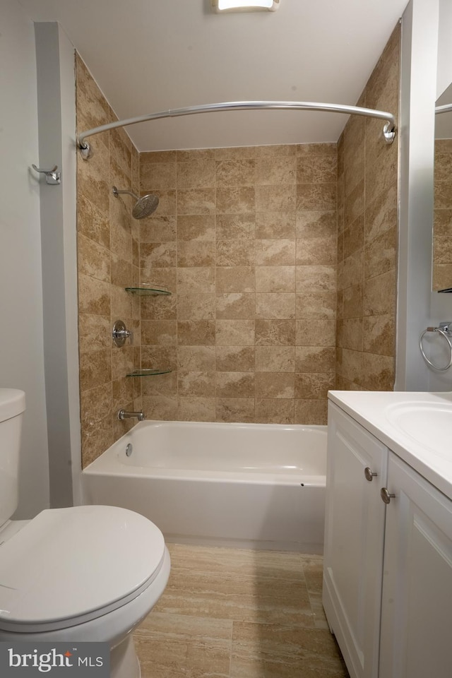 full bathroom featuring vanity, tiled shower / bath combo, and toilet