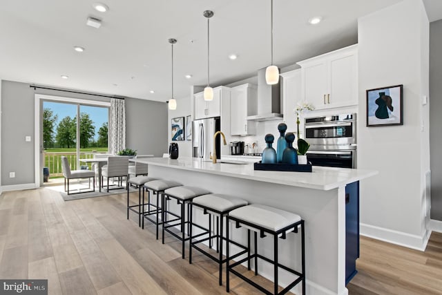 kitchen with white cabinetry, stainless steel appliances, an island with sink, and hanging light fixtures