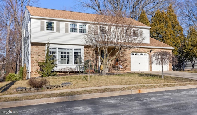 colonial inspired home with a garage, brick siding, driveway, roof with shingles, and a front yard