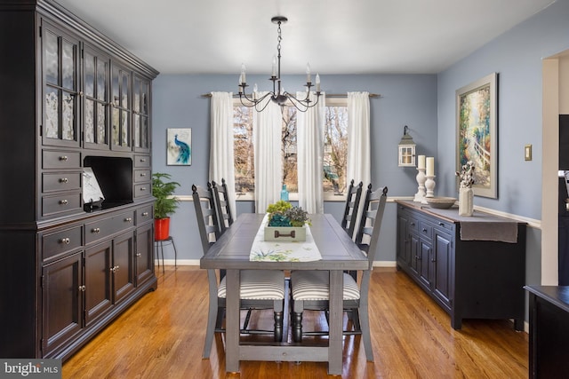 dining space with baseboards, a notable chandelier, and light wood-style floors