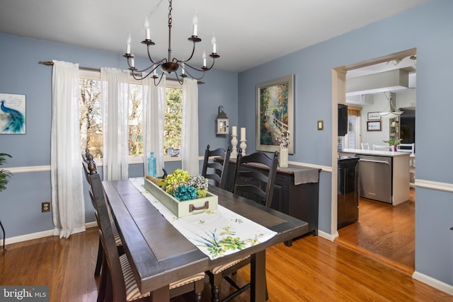 dining space with baseboards, wood finished floors, and a notable chandelier