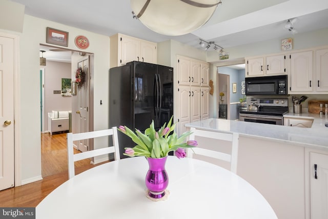 kitchen with black appliances, light countertops, white cabinets, and light wood-style floors