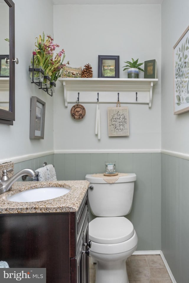 half bath featuring toilet, vanity, and wainscoting