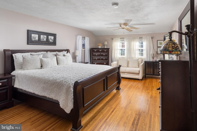 bedroom featuring a textured ceiling, a ceiling fan, and light wood-style floors