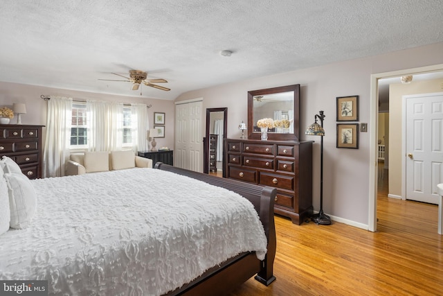 bedroom with baseboards, ceiling fan, wood finished floors, a textured ceiling, and a closet