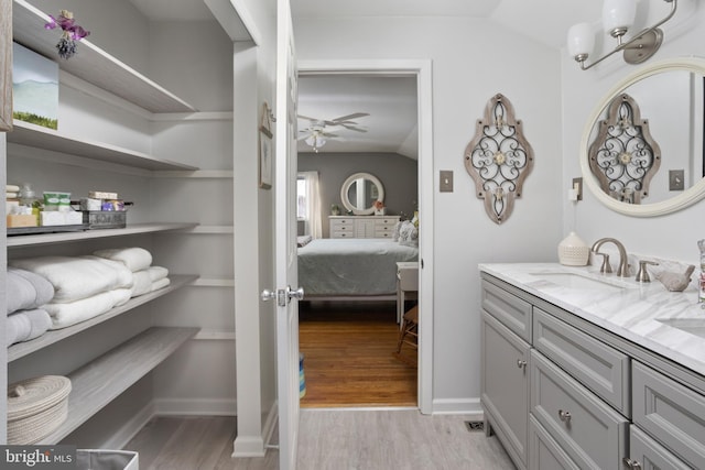 bathroom with a ceiling fan, vaulted ceiling, vanity, and wood finished floors