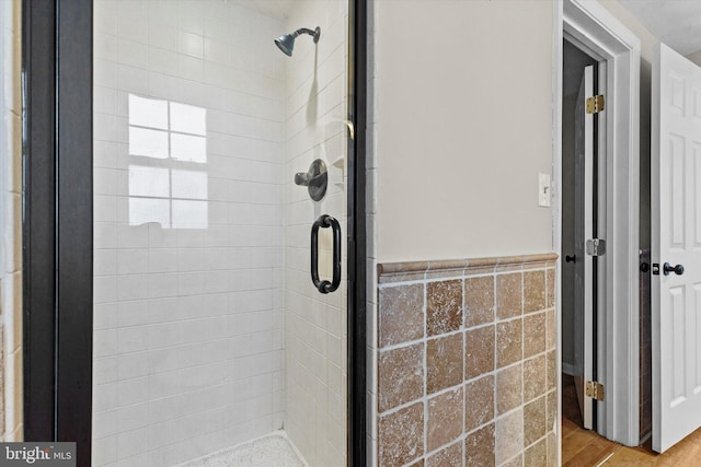 bathroom featuring an enclosed shower, hardwood / wood-style floors, and tile walls