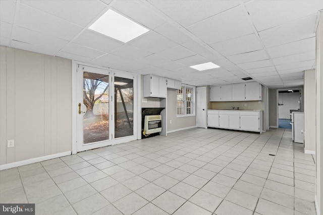 unfurnished living room with heating unit and a paneled ceiling