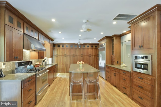 kitchen featuring appliances with stainless steel finishes, backsplash, a kitchen bar, a center island, and light hardwood / wood-style floors