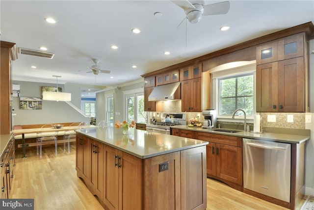 kitchen featuring extractor fan, appliances with stainless steel finishes, decorative light fixtures, sink, and a center island