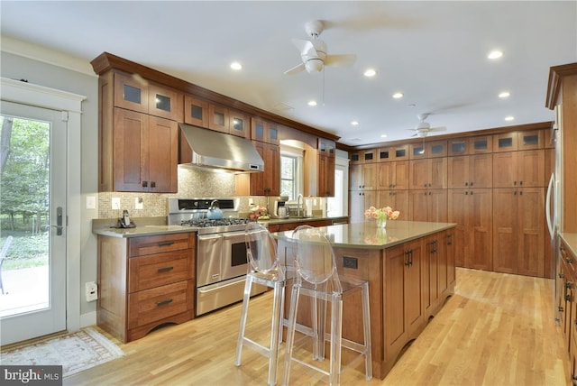 kitchen featuring extractor fan, a center island, light wood-type flooring, double oven range, and backsplash