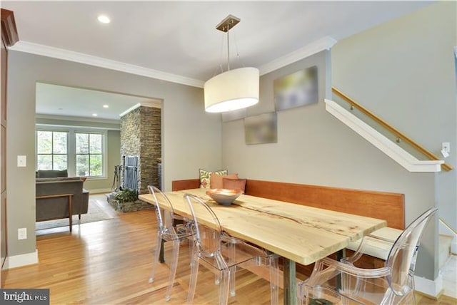 dining space featuring ornamental molding, a fireplace, and light hardwood / wood-style floors