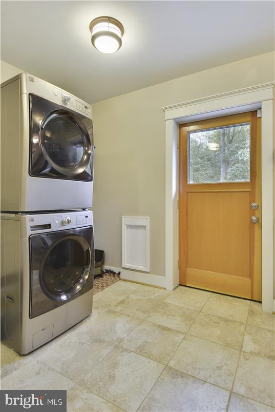 washroom with stacked washing maching and dryer