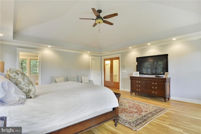 bedroom with ceiling fan, ornamental molding, light hardwood / wood-style floors, and a tray ceiling