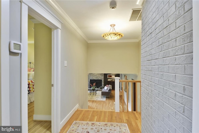 hallway with ornamental molding, brick wall, and light hardwood / wood-style floors