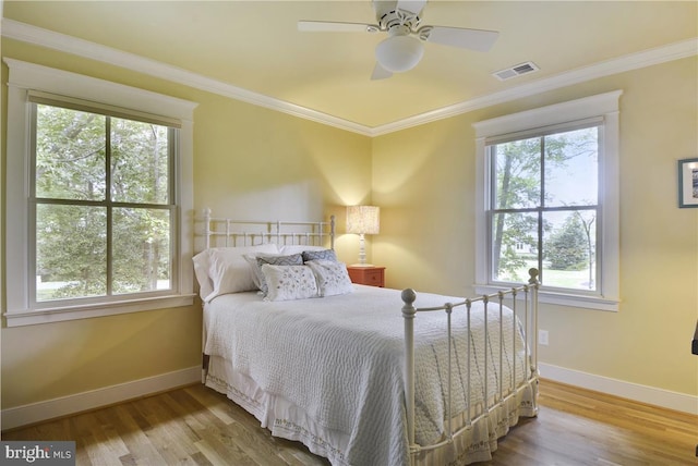 bedroom with ceiling fan, ornamental molding, and wood-type flooring