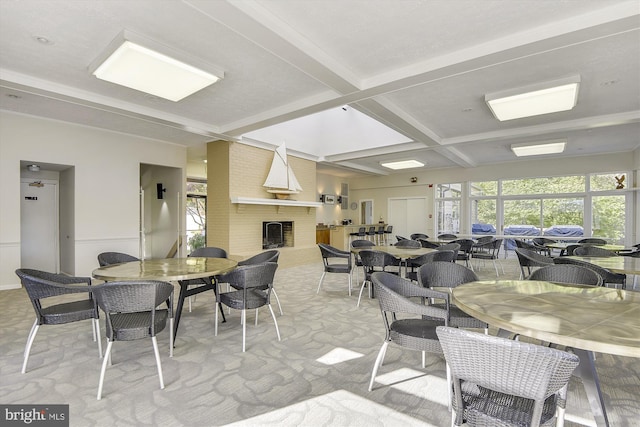 dining space with coffered ceiling, a brick fireplace, and beamed ceiling