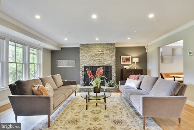 living room with crown molding, a fireplace, and light hardwood / wood-style flooring