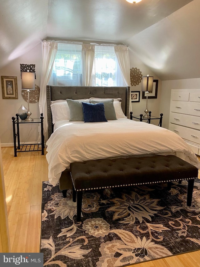 bedroom featuring lofted ceiling, light wood-style flooring, and baseboards