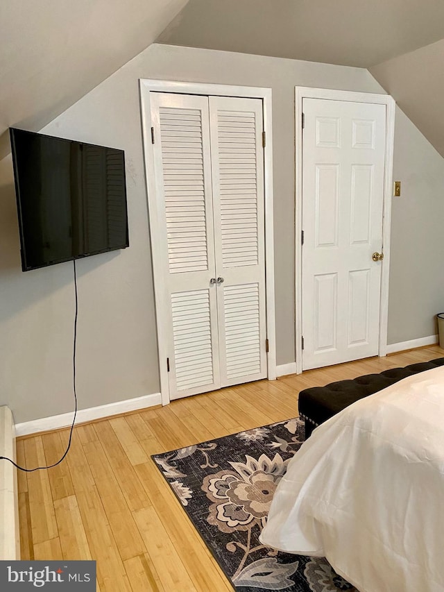 bedroom with lofted ceiling, wood finished floors, and baseboards