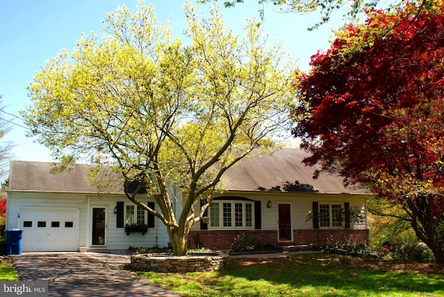 view of front facade with a garage, a front yard, brick siding, and driveway