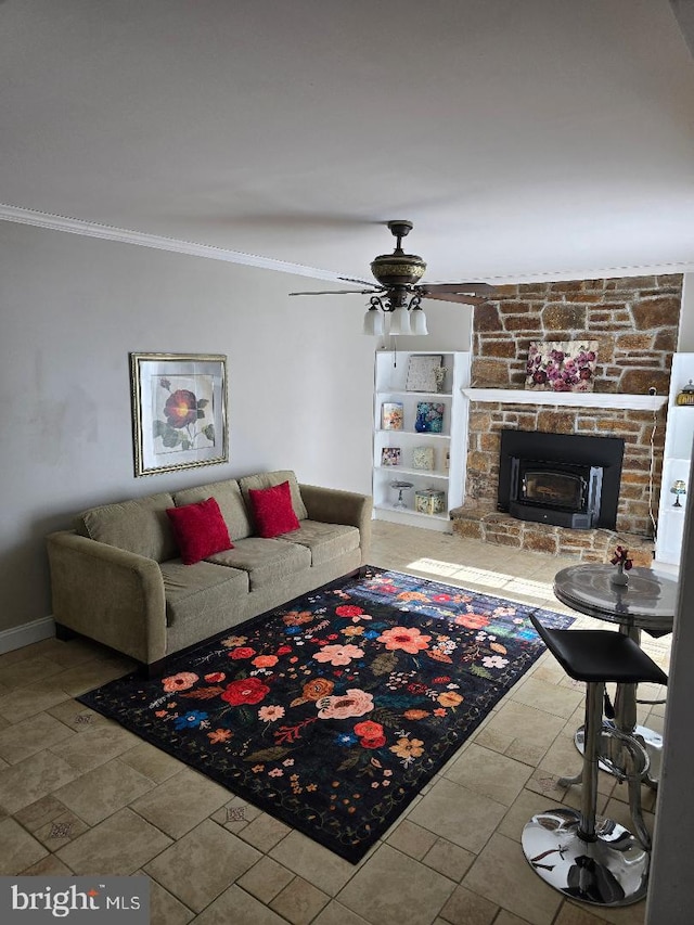 living area with ceiling fan, a stone fireplace, baseboards, and crown molding