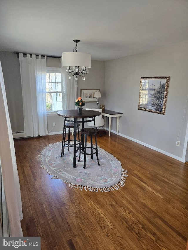 dining area featuring a chandelier, baseboard heating, wood finished floors, and baseboards