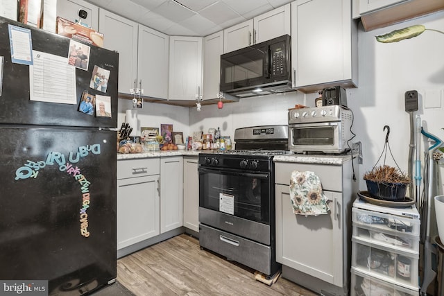 kitchen featuring white cabinets, light wood-type flooring, and black appliances