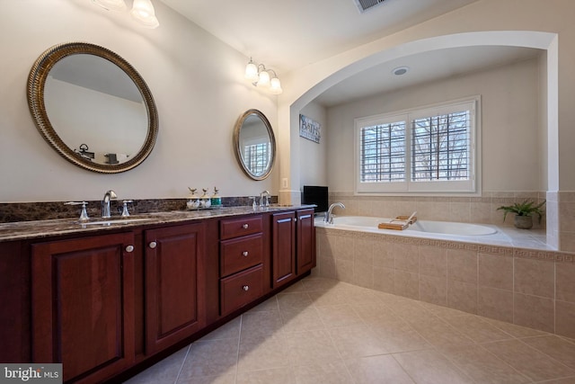 bathroom featuring a relaxing tiled tub, tile patterned floors, and vanity