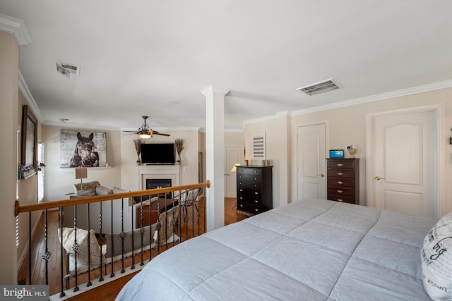 bedroom with hardwood / wood-style flooring, ornamental molding, and decorative columns