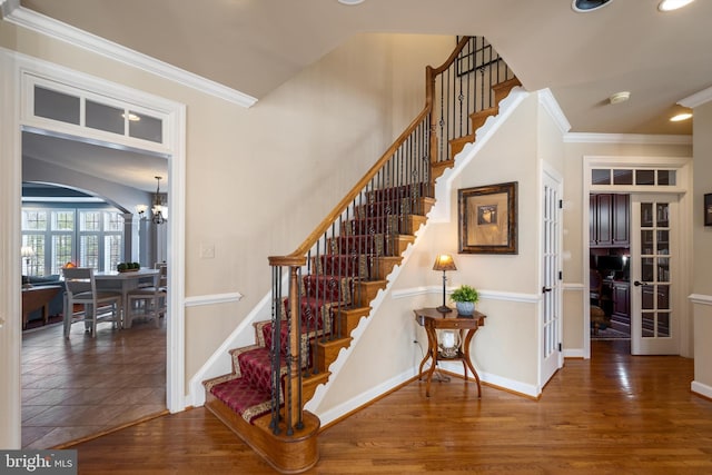 stairway featuring hardwood / wood-style flooring, ornamental molding, and a chandelier